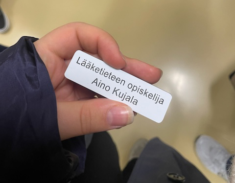 Ainon nimikyltti kädessä. Kyltissä lukee Lääketieteen opiskelija aino Kujala.