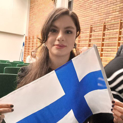 Ghazale liikuntasalissa Suomen lippu kädessä.
