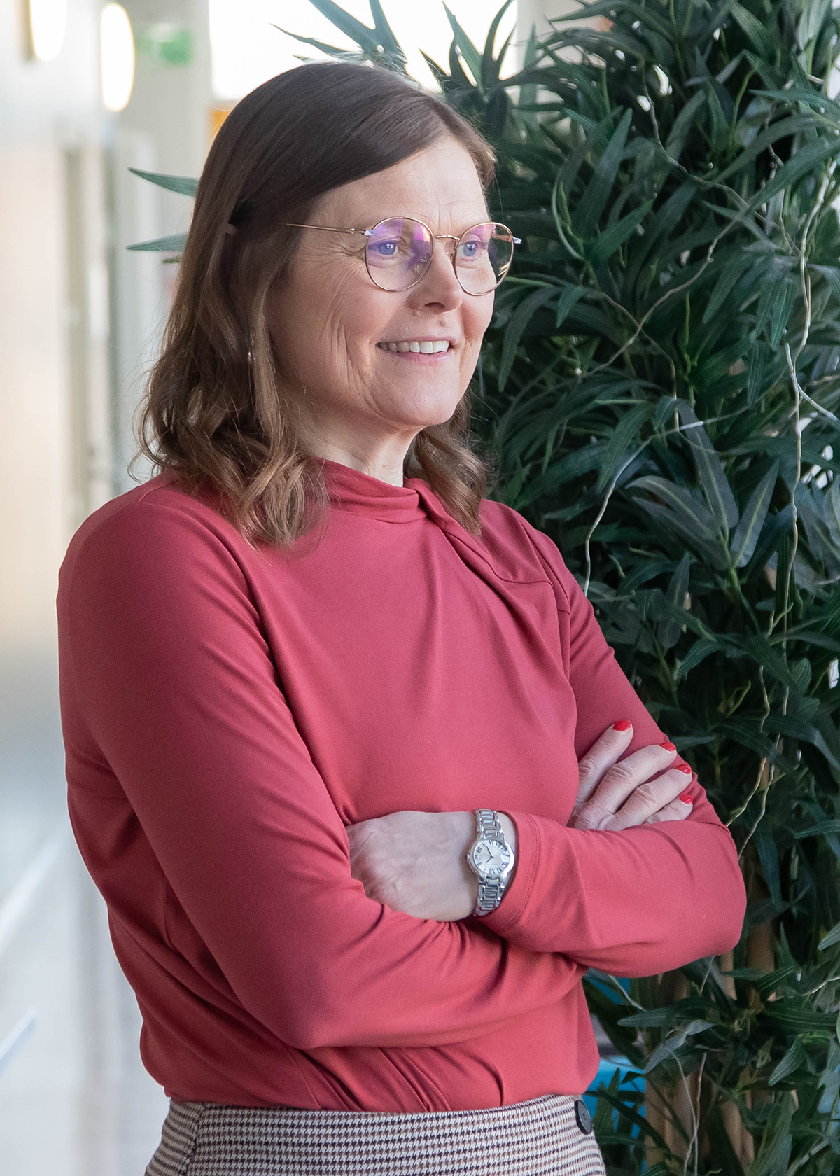 Jaana Laitila Helmi-rakennuksessa. Oikealla puolella viherkasvi.