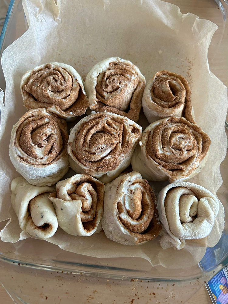 Cinnamon rollseja (pullia) lasisessa vuuassa leivinpaperin päällä.